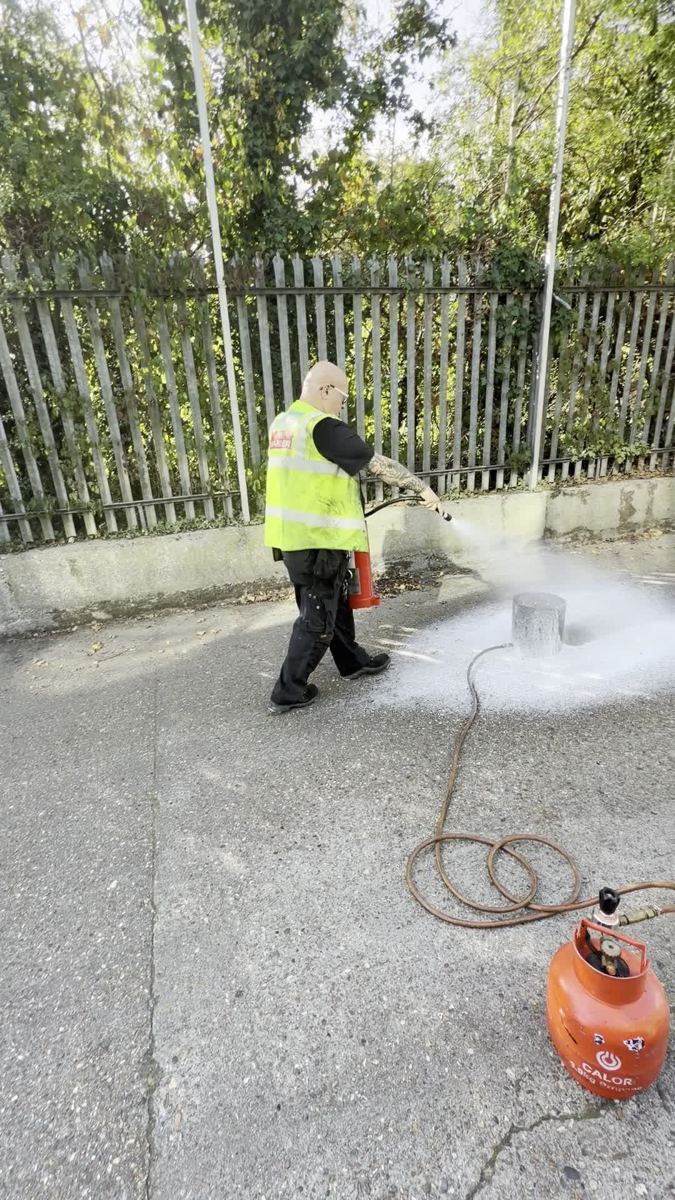 Trainee in a hi-vis vest putting out a live gas fire with an extinguisher