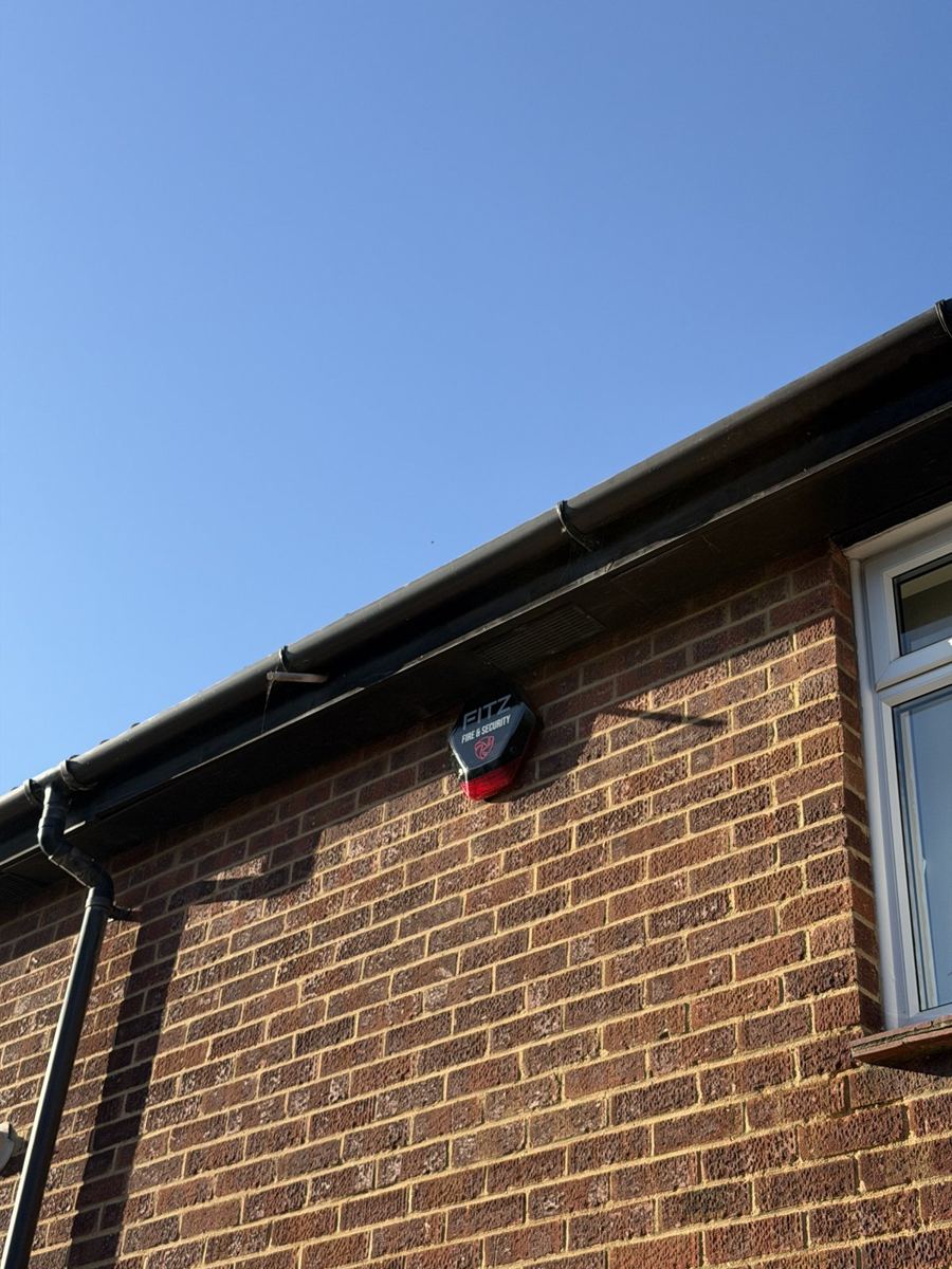 Intruder alarm external sounder fitted high on the brick wall of a house